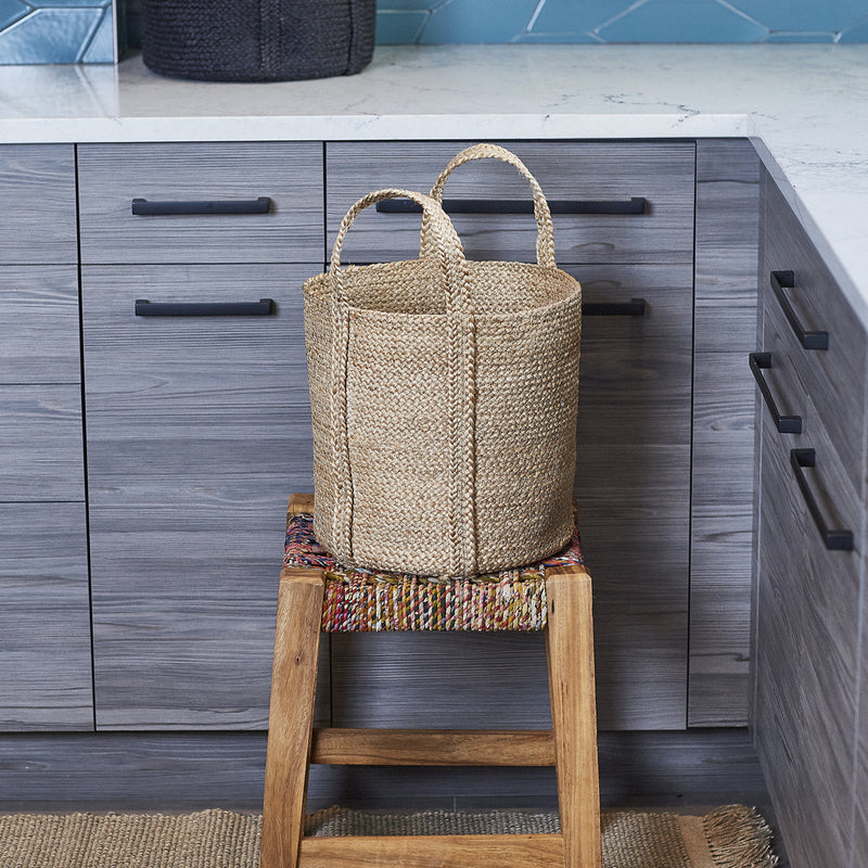Woven basket on a wooden stool in modern kitchen with gray cabinets and countertop.
