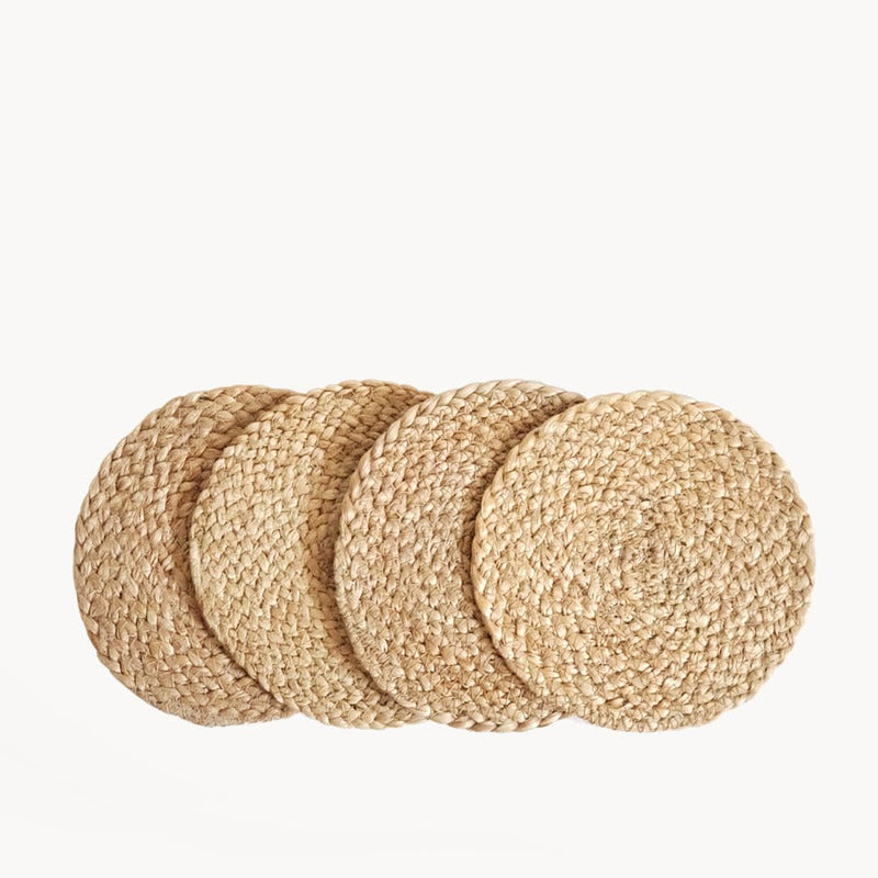 Set of four round woven straw placemats for dining table decor.