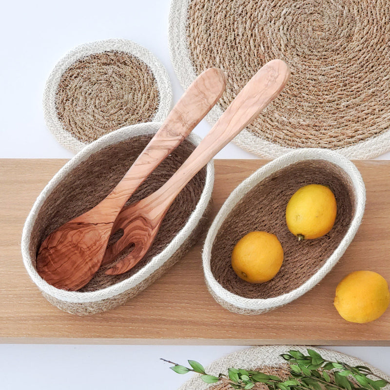 Natural woven baskets with wooden utensils and lemons on a wooden surface.
