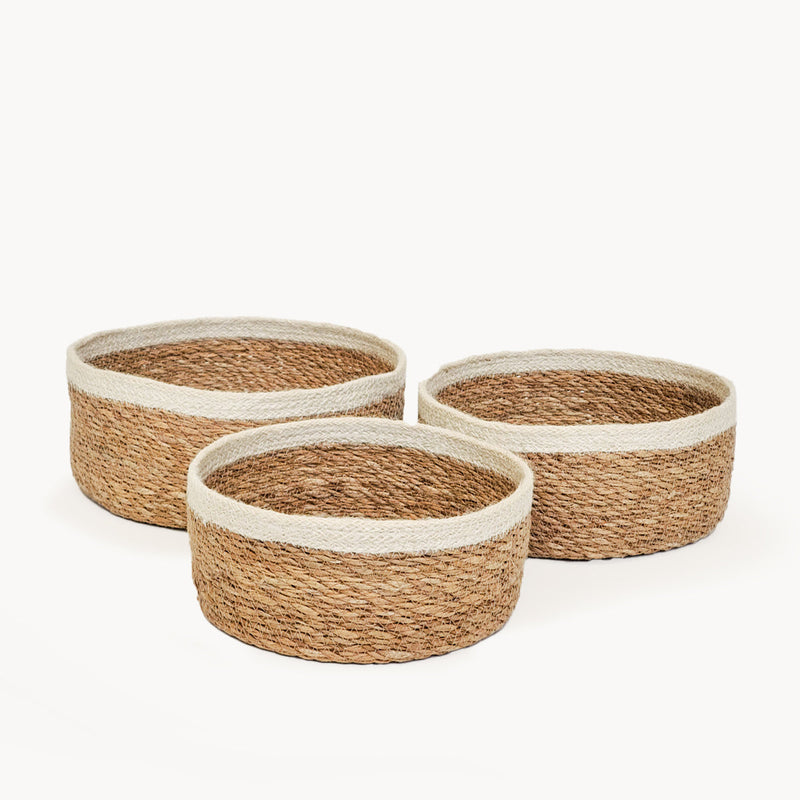 Three round natural woven baskets with white trim, perfect for home storage and decor.