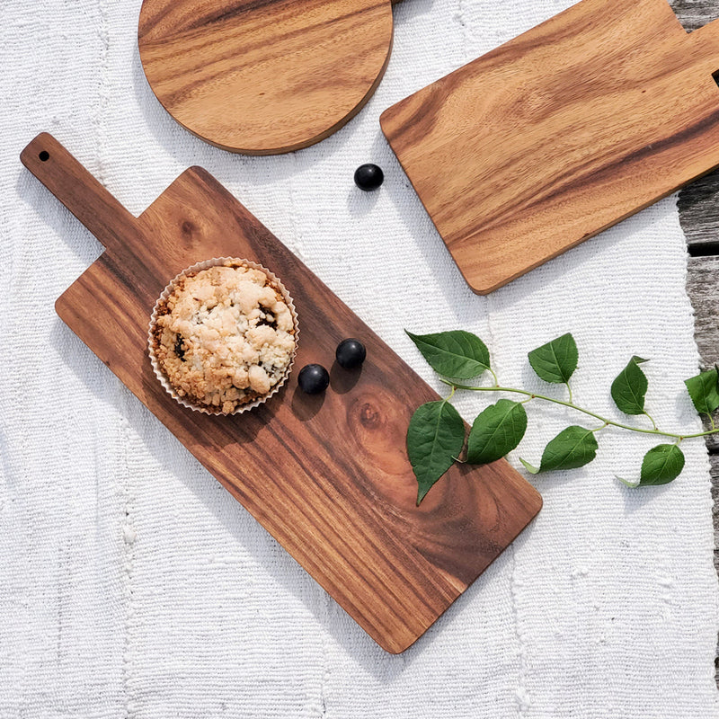 Wooden serving boards with a muffin and berries on a textured white cloth, ideal for rustic kitchen decor.