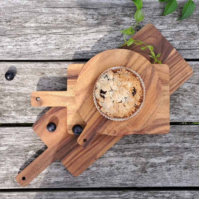 Blueberry streusel muffin on wooden serving boards with scattered blueberries on rustic table background.