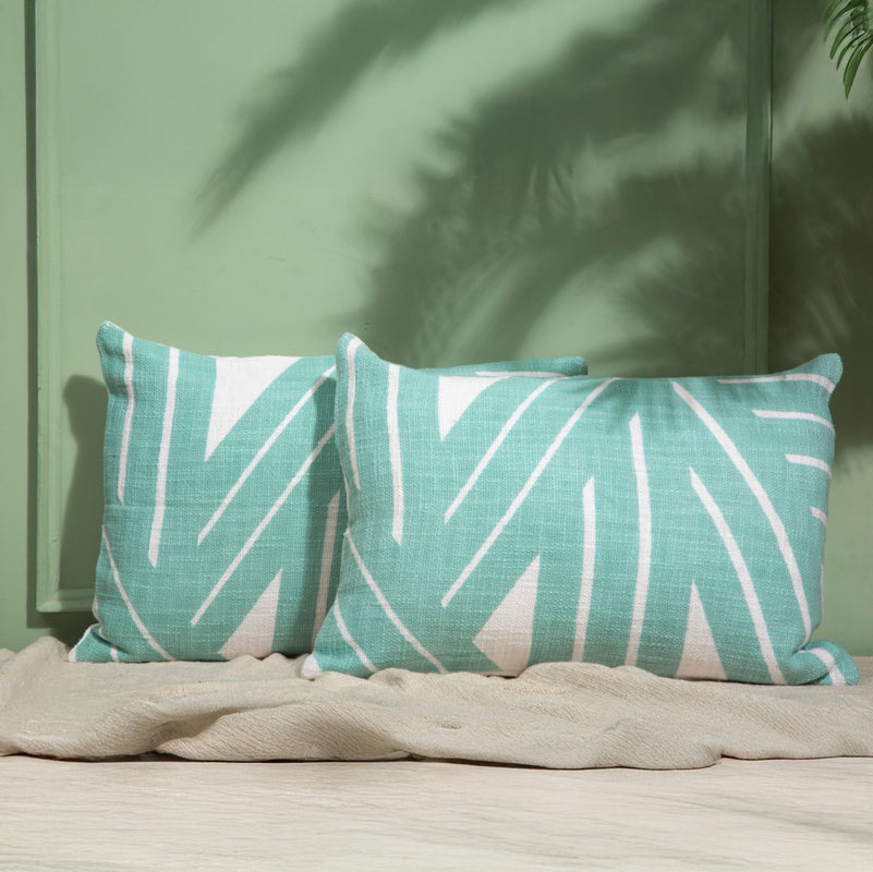 Decorative green and white striped throw pillows on a beige sofa in a modern living room setting.