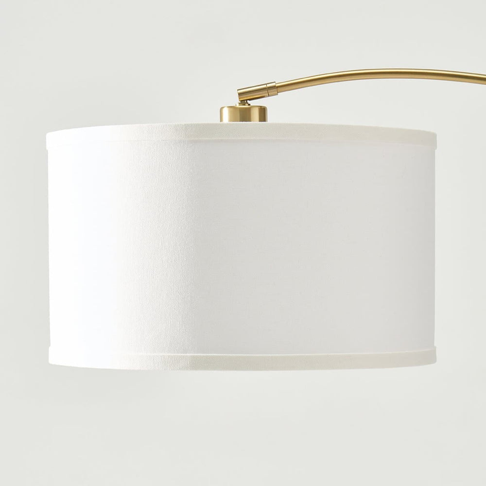 Elegant white lampshade with brass arm for modern home lighting.