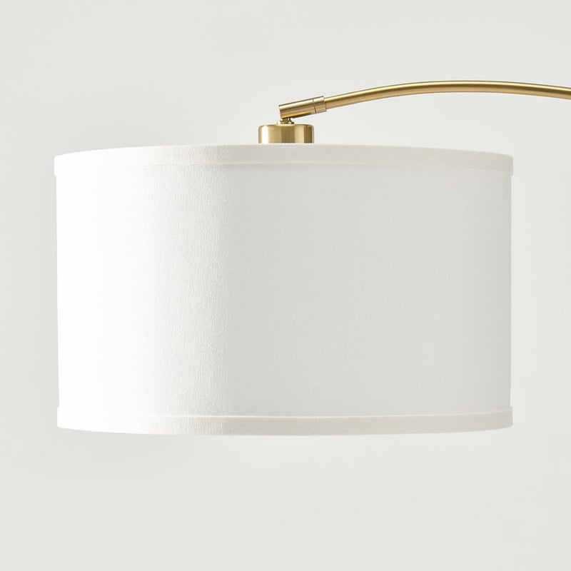 Elegant white lampshade with brass arm for modern home lighting.