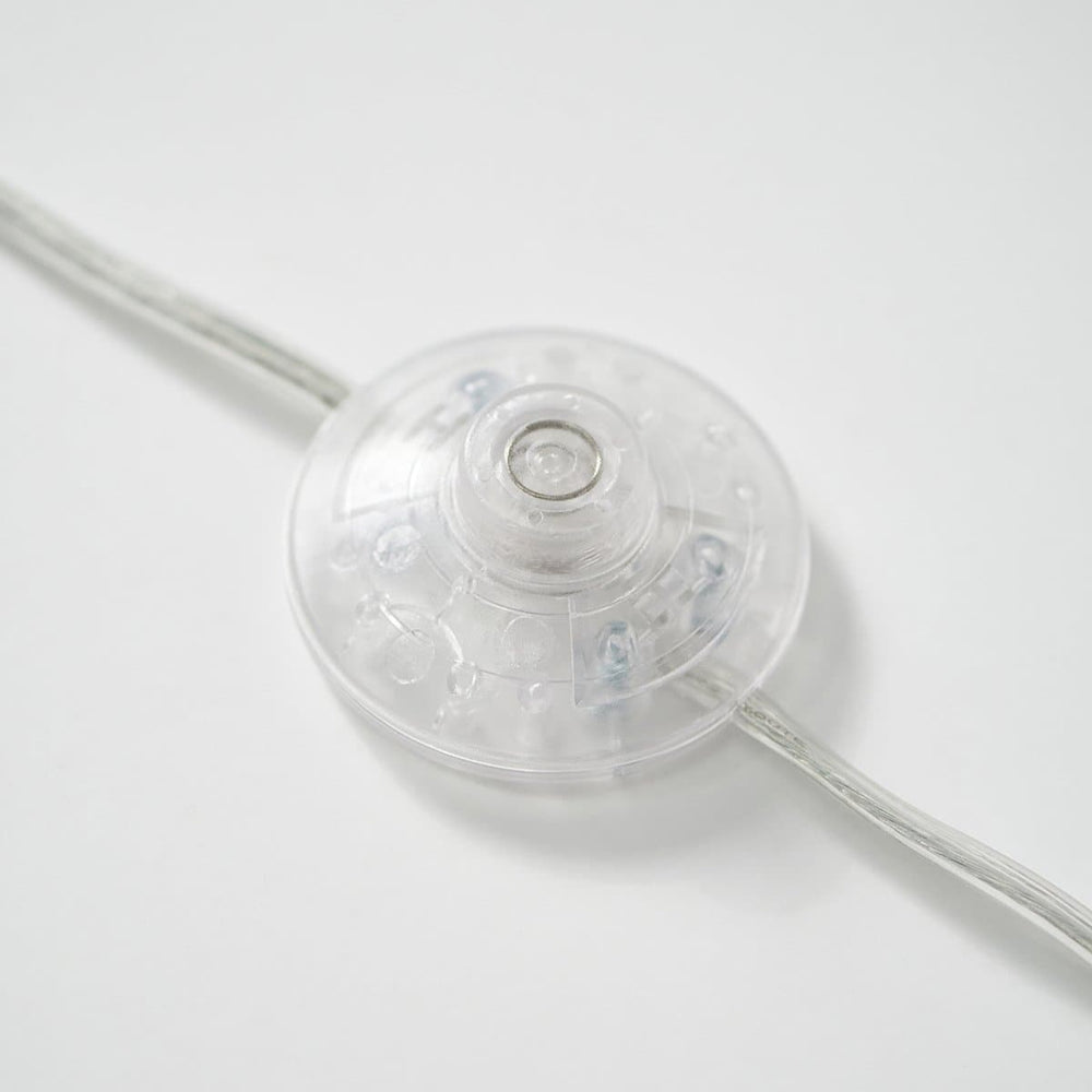 Clear circular light switch with wire on white background.