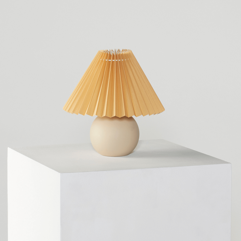 Vintage-style table lamp with pleated lampshade on a modern white pedestal.