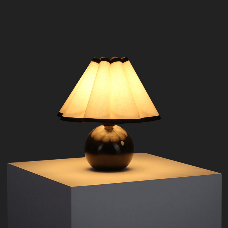 Elegant modern table lamp with warm yellow light on a dark background.