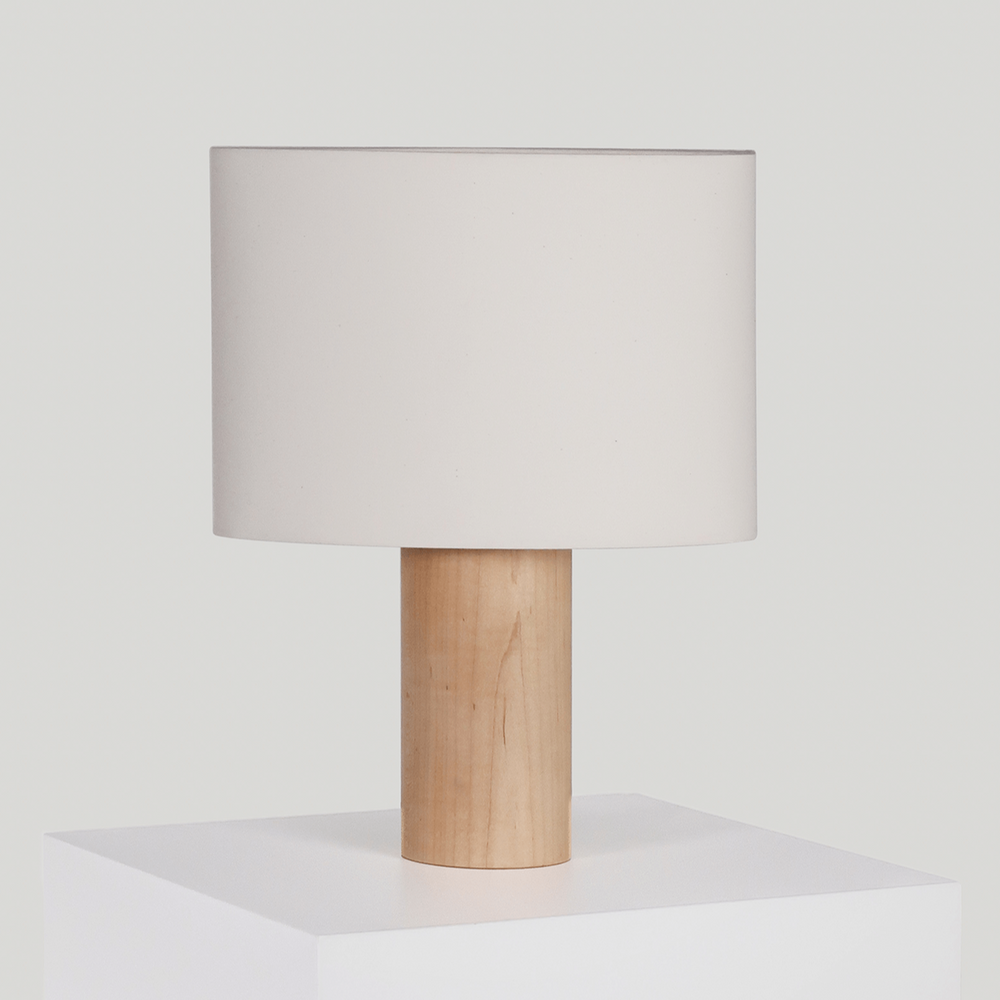 Minimalist wooden table lamp with a white fabric shade on a white surface.
