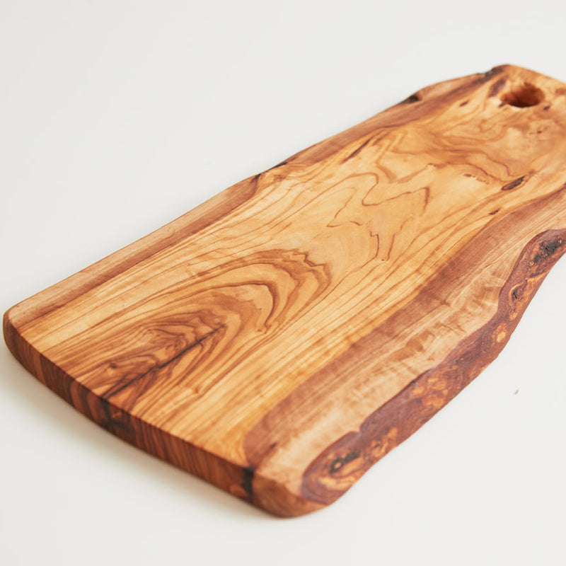 Natural olive wood cutting board with rustic grain pattern for kitchen use.