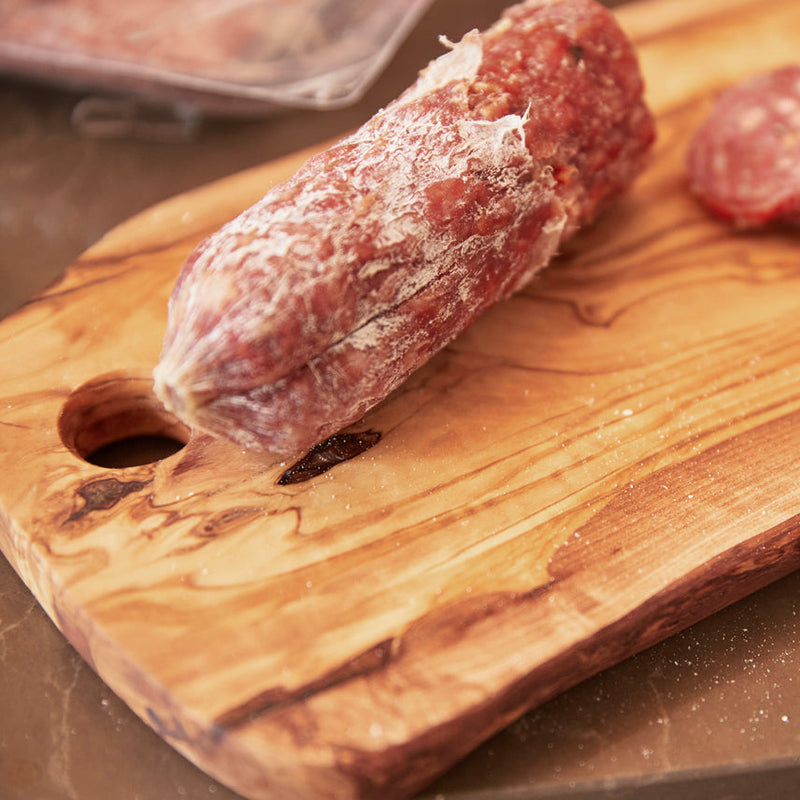 Dry-cured salami on a rustic wooden cutting board.