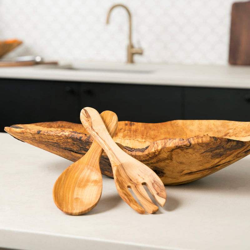 Olive wood salad bowl and utensils on a modern kitchen countertop.