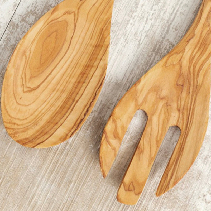 Olive wood salad fork and spoon set on rustic wooden background.