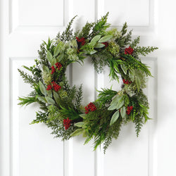 Christmas wreath of mixed evergreen cedar and eucalyptus with red berry clusters hanging on a white paneled front door