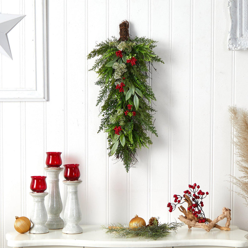 Christmas greenery swag wall hanging with red berries and eucalyptus over white beadboard mantel table with red candle holders and gold ornaments holiday decor
