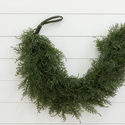 Lush natural evergreen wreath with cedar branches hanging on white shiplap wall, rustic farmhouse Christmas door decor