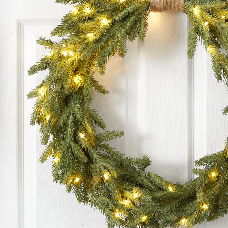 Green pine Christmas wreath with warm white LED string lights hanging on a white paneled front door, festive holiday decor