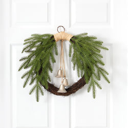 Rustic twig Christmas wreath with cascading evergreen branches and three hanging silver bells on a white paneled door, farmhouse holiday door decor
