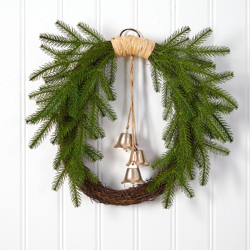Rustic evergreen grapevine Christmas wreath with hanging brass bells on white paneled door, farmhouse holiday door decor