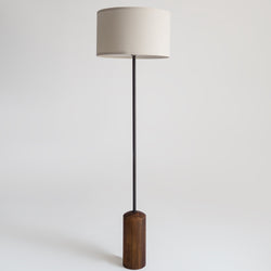 Minimal modern floor lamp with white fabric drum shade, slim black metal pole and walnut wood cylindrical base for living room or reading nook