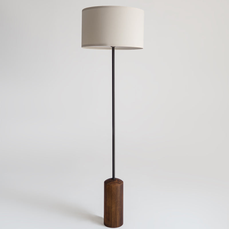 Minimal modern floor lamp with white fabric drum shade, slim black metal pole and walnut wood cylindrical base for living room or reading nook