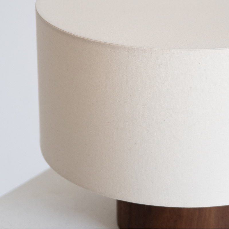Minimalist beige fabric drum table lamp with walnut wood round base, neutral bedside accent lighting