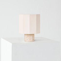 Minimalist geometric pale-pink table lamp with faceted shade and speckled stone base on white pedestal