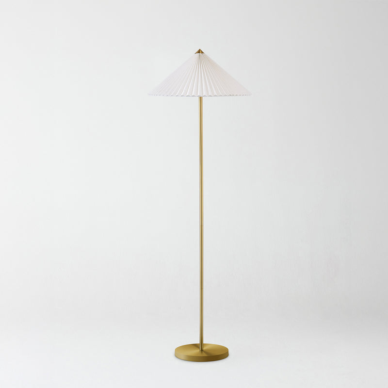 Modern brass floor lamp with slim stem and white pleated conical shade on a minimalist white background