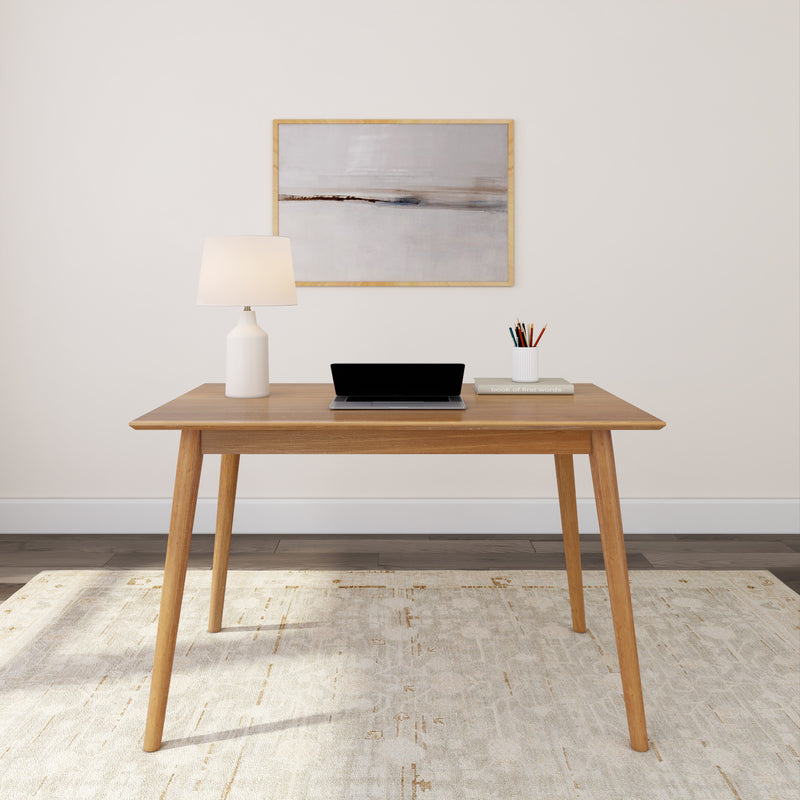 Minimalist home office setup with wooden desk, laptop, desk lamp, and art piece.