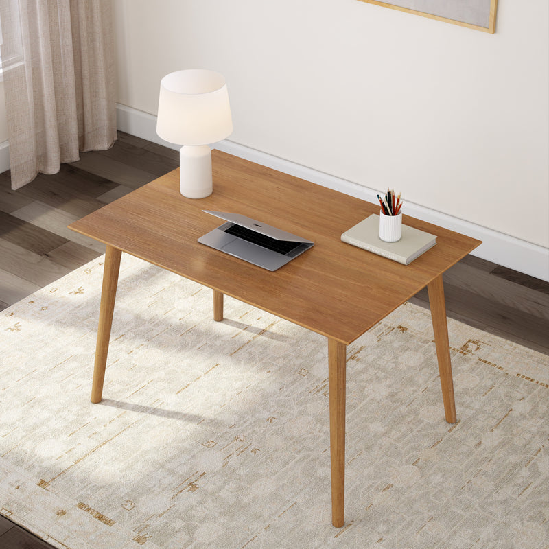 Wooden desk with modern lamp, laptop, books, and pencils in a stylish home office setting.