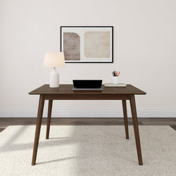 Mid-century modern office desk with laptop, lamp, and artwork on wall.