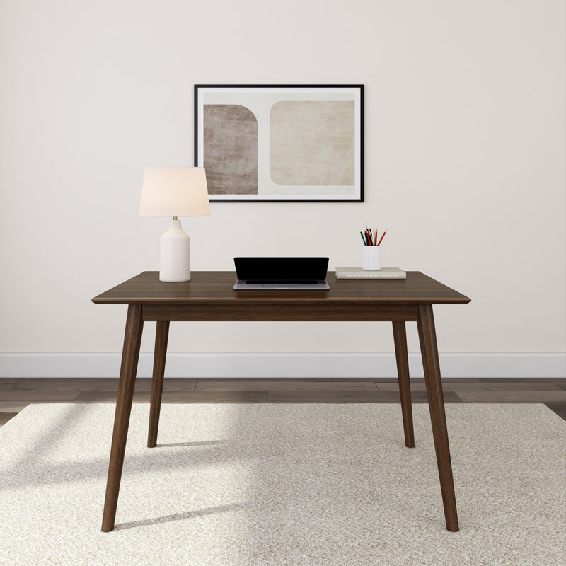 Mid-century modern office desk with laptop, lamp, and artwork on wall.