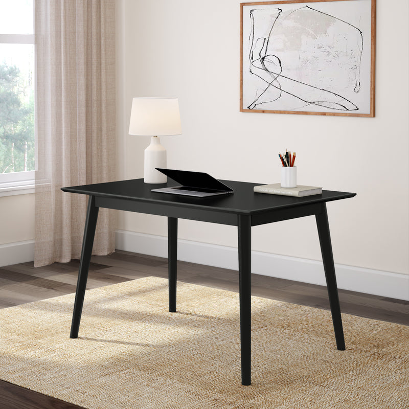 Minimalist black desk in modern home office with laptop, lamp, and wall art.