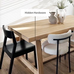 Solid oak dining table with hidden hardware, black wood chair and boucle accent chair, ceramic vases and brass candlesticks