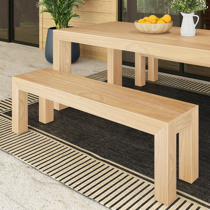 Natural wood dining bench and table set on a stylish patio rug, with modern decor elements.