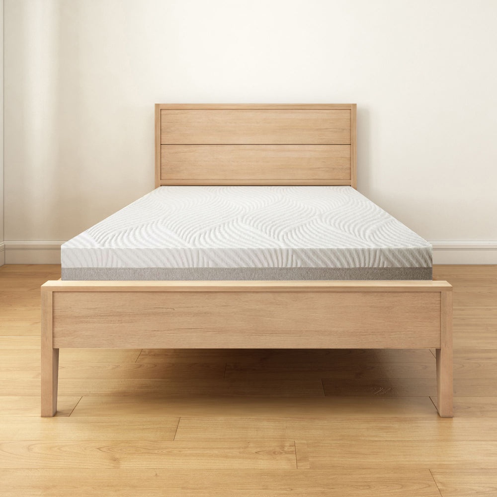 Wooden bed frame with plush mattress in minimalist bedroom setting.