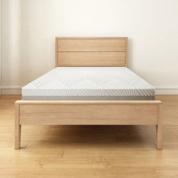 Wooden bed frame with plush mattress in minimalist bedroom setting.