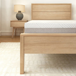 Wooden bed frame with modern nightstand and lamp in a cozy bedroom setting.