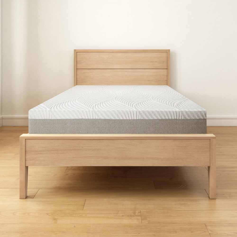 Wooden bed frame with comfortable mattress in minimal modern bedroom setting.