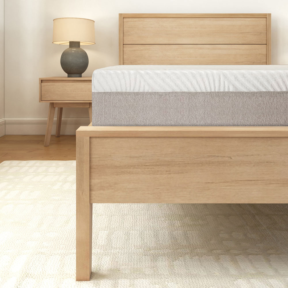 Wooden bed frame with mattress and a modern nightstand featuring a lamp, perfect for bedroom decor.