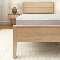 Modern wooden bed frame with mattress and nightstand in a cozy bedroom setting.