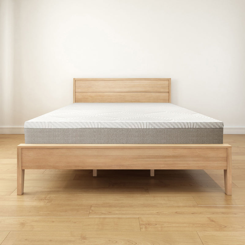 Wooden bed frame with a memory foam mattress in a minimalist bedroom setting.