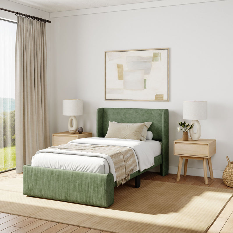 Modern bedroom with green upholstered bed, beige bedding, abstract wall art, and wooden nightstands, featuring natural light and cozy decor.
