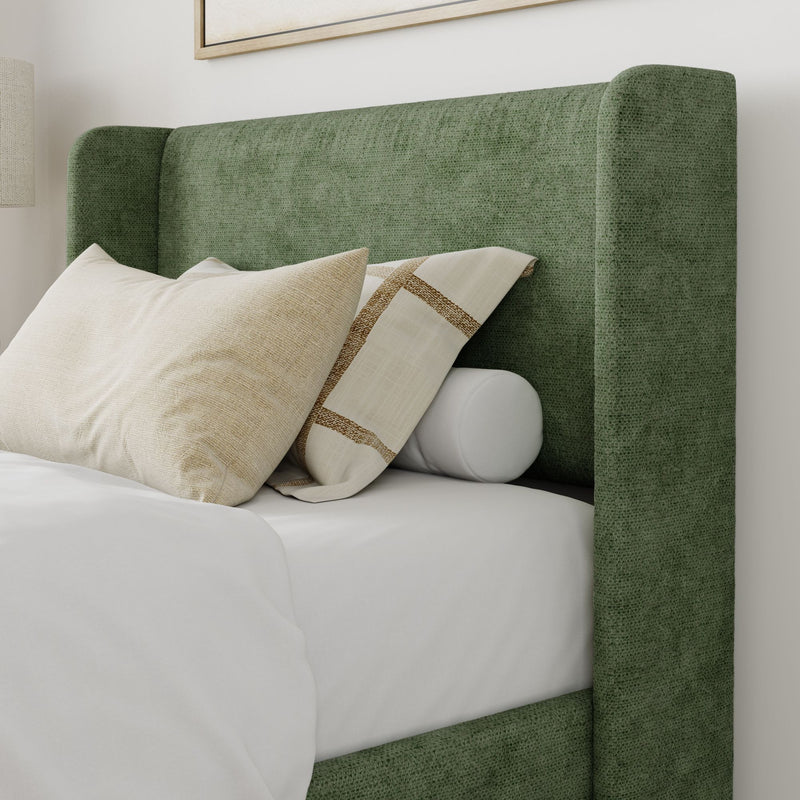 Green upholstered bed with beige and white pillows in a modern bedroom setting.