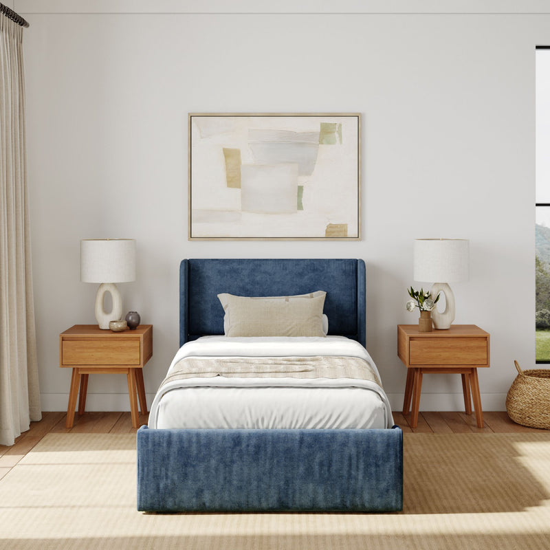 Modern bedroom interior with a blue upholstered bed, abstract wall art, and wooden nightstands.