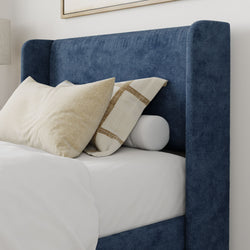 Blue fabric upholstered bed with beige decorative pillows in a modern bedroom setting.