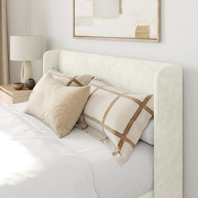Modern bedroom with upholstered headboard, patterned pillows, and minimalist decor.