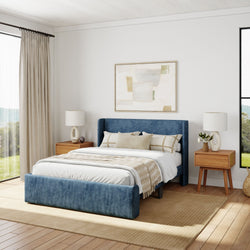 Modern bedroom interior with blue upholstered bed, wooden nightstands, and neutral decor.