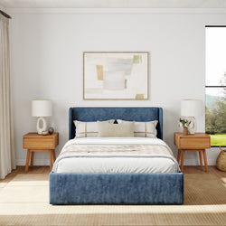 Modern bedroom design with a blue upholstered bed, wooden nightstands, and neutral decor elements.