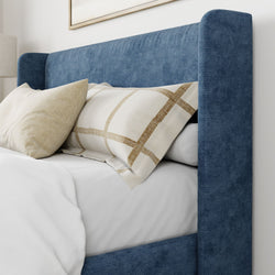 Luxurious blue upholstered bed with beige pillows and white bedding in a modern bedroom setting.